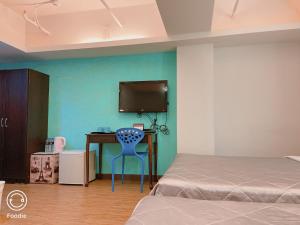 a bedroom with a blue chair and a desk with a tv at 戀真會館 in Taichung