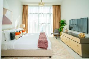 a bedroom with a large bed and a flat screen tv at Fantastay Spacious 3 BDR plus maids with Burj Khalifa View in Dubai