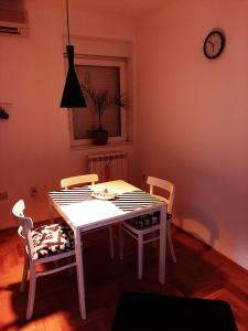 uma sala de jantar com mesa e cadeiras e um relógio em Apartments best city place em Belgrado