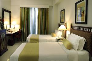 um quarto de hotel com duas camas e uma secretária em Avari Xpress, Islamabad em Rawalpindi