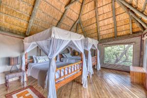 1 dormitorio con cama con dosel y suelo de madera en Mbali Mbali Soroi Serengeti Lodge, en Banagi