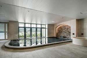 a swimming pool in a large room with a bath tub at Lequ Okinawa Chatan Spa ＆ Resort in Chatan