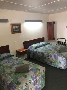 a hotel room with two beds and a table at Blackall Coolibah Motel in Blackall