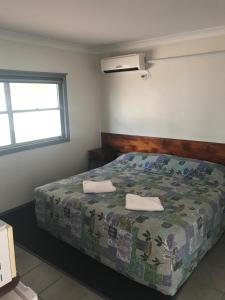 a bedroom with a bed with two towels on it at Blackall Coolibah Motel in Blackall