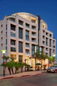 a large building with palm trees in front of it at Crowne Plaza Haifa by IHG in Haifa