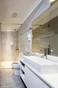 a bathroom with a toilet, sink, and shower stall at Queens Hotel II in Taipei