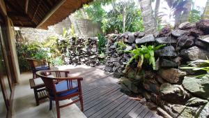 a patio with two chairs and a stone wall at Villa Pantulan Bali in Ubud