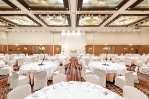 un salón de banquetes con mesas y sillas blancas y lámparas de araña en ANA Crowne Plaza Hotel Kushiro, an IHG Hotel en Kushiro