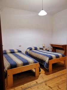 2 letti in una camera con scrivania e tavolo di Appartamenti Violalpina - Piazza Costanzi a Malè