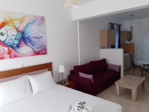 a bedroom with a bed and a couch and a painting at Olive Tree Apartments in Parga