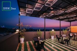 een patio met tafels en stoelen op een balkon in de nacht bij SERENE Stays Hotel in Yangon