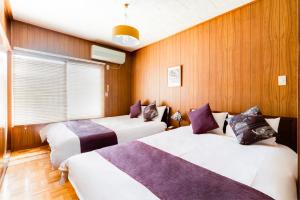 twee bedden in een kamer met houten wanden bij Chikyuutabikazoku USJ in Osaka +56 foto's