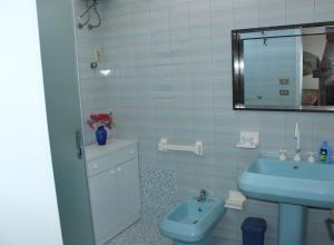 y baño con lavabo azul y espejo. en Splendida casa con vista sulla Baia di Gallipoli, en Nardò