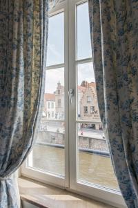 a window with curtains and a view of the water at Hotel De Orangerie - Small Luxury Hotels of the World in Bruges