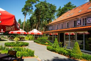 une cour avec des tables et des parasols et un bâtiment dans l'établissement Ani Pensjonat, à Borne Sulinowo