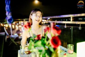 a woman sitting at a table with a vase of flowers at Khách sạn Sunrise Ninh Thuận in Thôn Dư Khánh +105 photos