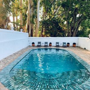 einen Pool mit Stühlen und Bäumen im Hintergrund in der Unterkunft Blaauwklippen Manor by NEWMARK in Stellenbosch