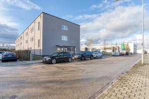 un estacionamiento con autos estacionados frente a un edificio en NYCE Hotel Ingolstadt, en Ingolstadt