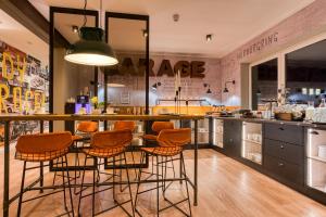 a kitchen with a bar with orange chairs around it at NYCE Hotel Ingolstadt in Ingolstadt