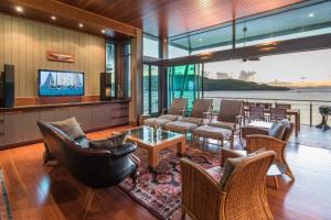 a living room with couches and chairs and a television at Yacht Club 19 Villa Bijou De Mer Ocean Front Private Pool 2 Buggies in Hamilton Island