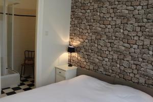 1 dormitorio con una pared de piedra, 1 cama y 1 lámpara en En Suite en The Hague