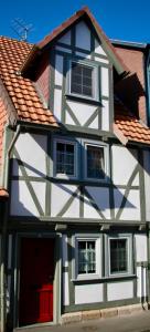 ein weißes und schwarzes Haus mit einer roten Tür in der Unterkunft Mittelalterliches Fachwerkhaus am Diebesturm - klimatisiert- in Bad Sooden-Allendorf