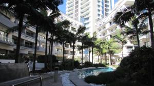 un complexe avec une piscine et des palmiers en face d'un bâtiment dans l'établissement St Julians Central luxury apartment, à San Ġiljan