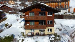 a house with a deck in the snow at Chalet Gerbera in Wengen