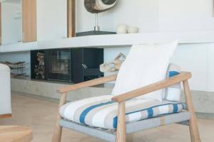uma cadeira de madeira numa sala de estar com lareira em Clifton 3rd Beach house - Breathtakingly Beautiful Views! em Cidade do Cabo