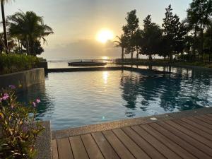 a swimming pool with a sunset in the background at Eyu@Timurbay Seaview Residence in Kuantan