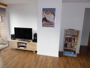 a living room with a television and a book shelf at Chalet Gerbera in Wengen