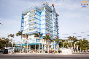 a tall blue building with a person on a motorcycle in front at Khách sạn Sunrise Ninh Thuận in Thôn Dư Khánh