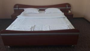 a bed with white sheets and pillows in a room at Izumrud in Uzhhorod