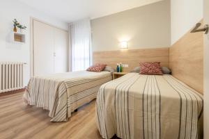 a hotel room with two beds and two lamps at Apartamentos Astoria in Tarragona