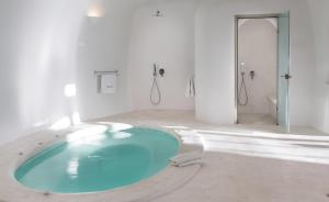 Habitación blanca con baño con bañera grande. en Perivolas Hotel en Oia