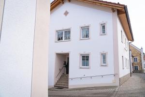 une maison blanche avec une grande porte ouverte dans l'établissement Pension Sengmüller, à Buchbach