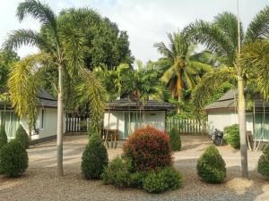 una casa con palmeras y arbustos delante de ella en Lung Pod 9 resort en Chumphon