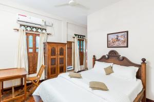 a bedroom with a white bed with a desk and a chair at Kumarakom Wood Castle Serviced Appartments in Kumarakom