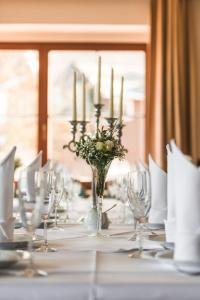 a long table with a vase of flowers and candles at Berghotel Friedrichshöhe - Sauna, Pool & Natur in Kurort Altenberg +69 photos