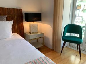 ein Schlafzimmer mit einem Bett und einem grünen Stuhl in der Unterkunft Baixa Pombalina - Deluxe Modern Apartment in Lissabon