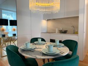 einen Esstisch mit grünen Stühlen und einem Kronleuchter in der Unterkunft Baixa Pombalina - Deluxe Modern Apartment in Lissabon