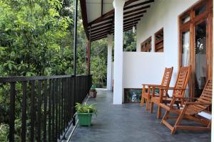 a porch with rocking chairs on a house at Amado Homestay Ella in Ella