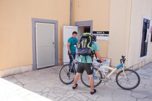 HI Hostel Pula في بولا: رجل يحمل حقيبة ظهر يقف بجوار دراجة