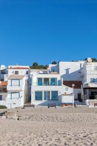 ein weißes Haus am Strand mit Sandstrand in der Unterkunft Residence Estrela do Mar in Salema