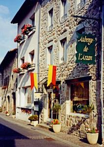 a building with flags on the side of a street at Auberge de l'Arzon in Chomelix