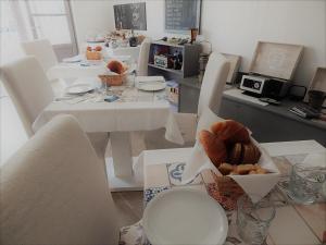 a dining room with white tables and chairs with a box of bread at B&B Piè del Castello in Levanto