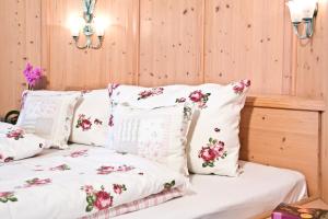 a bed with white pillows and pink flowers on it at Ferienwohnungen Gästehaus Schraudolf in Oberstdorf