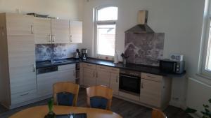 eine Küche mit weißen Schränken und einem Tisch und Stühlen in der Unterkunft Ferienwohnung "Burgblick" in Heldrungen