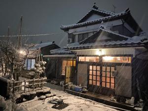 una casa asiática con nieve en el suelo delante de ella en Relaxing house de Akemi, en Shimminato
