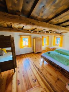 a bedroom with two beds and wooden floors and windows at Lerchnerhof in Eisentratten